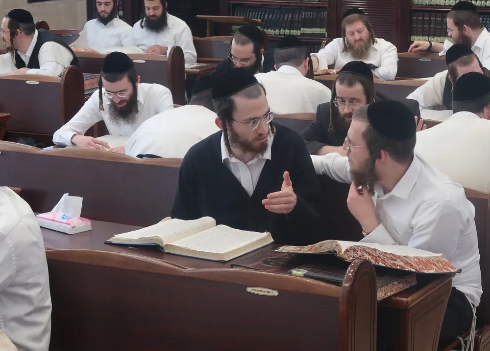 Yungeleit learning in chavrusos at rows of benches in the beis medrash of Kollel HaShakdanim, Beitar Illit
